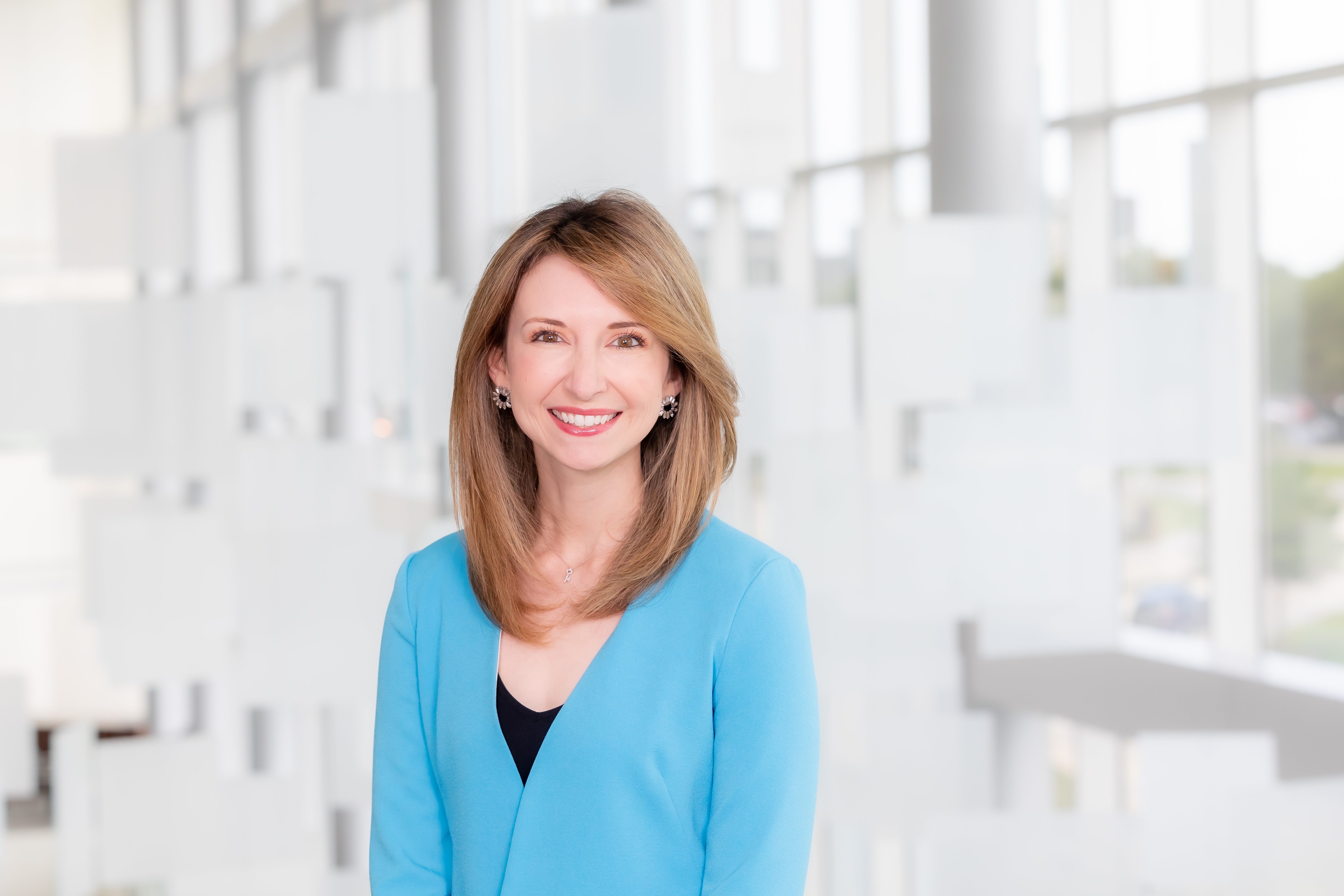 white woman with shoulder-length blonde hair, black shirt and bright blue sweater