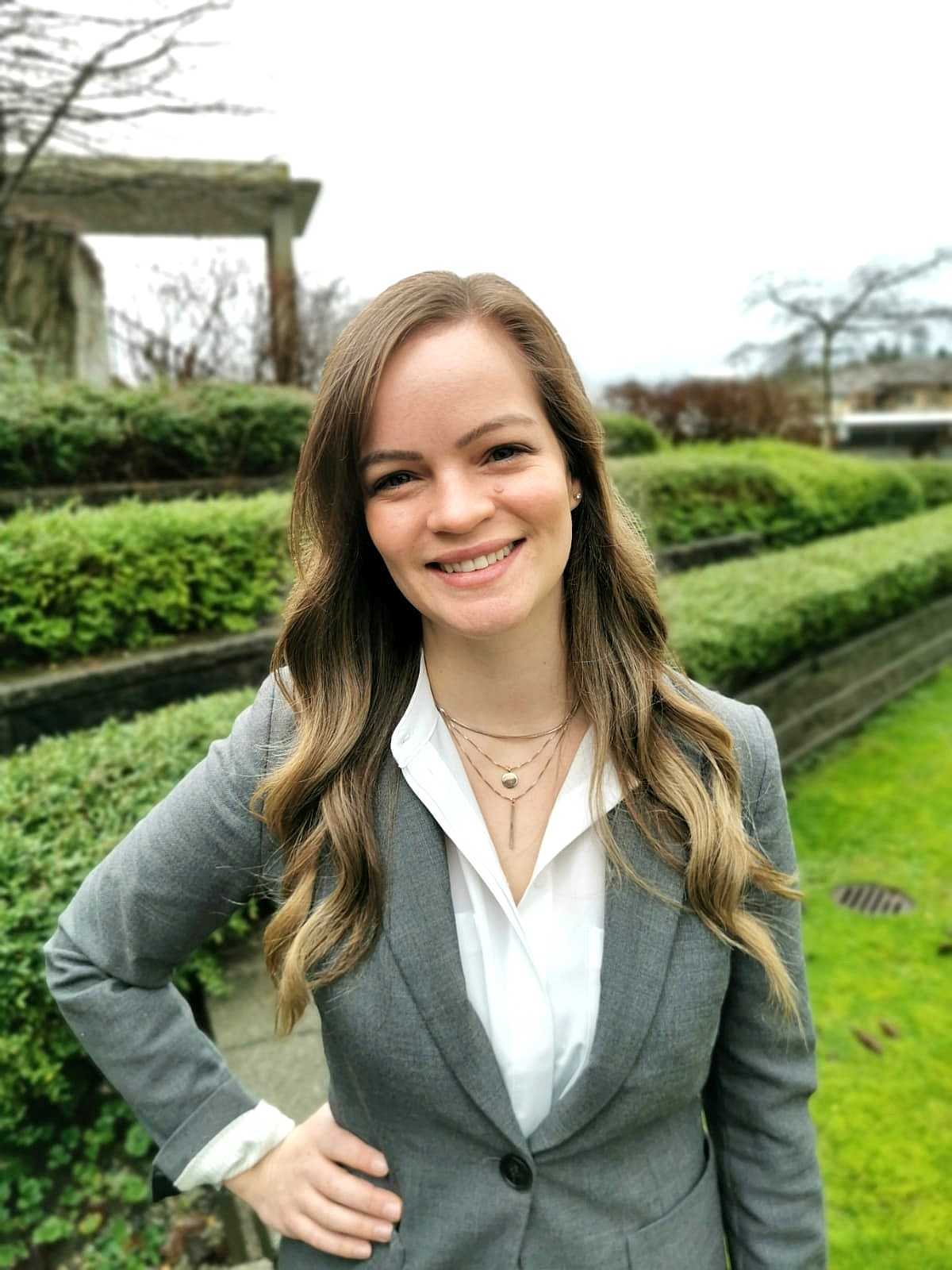 white woman, long blonde wavy hair, white blouse, gray blazer