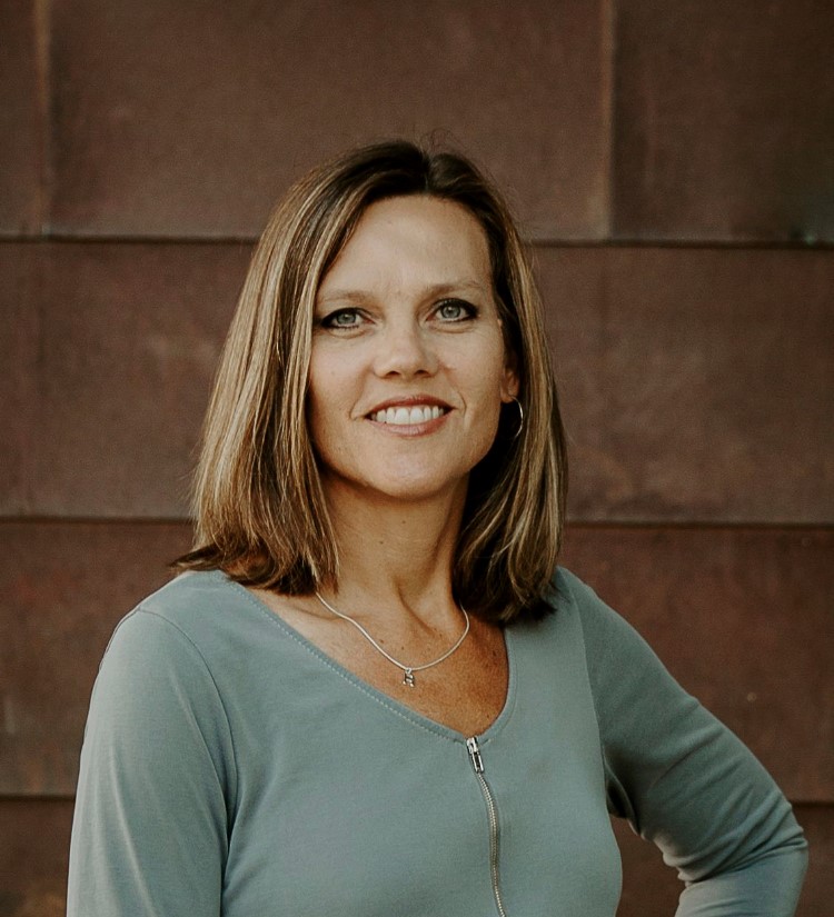 white woman with brown hair and blonde highlights wearing light green v-neck sweater