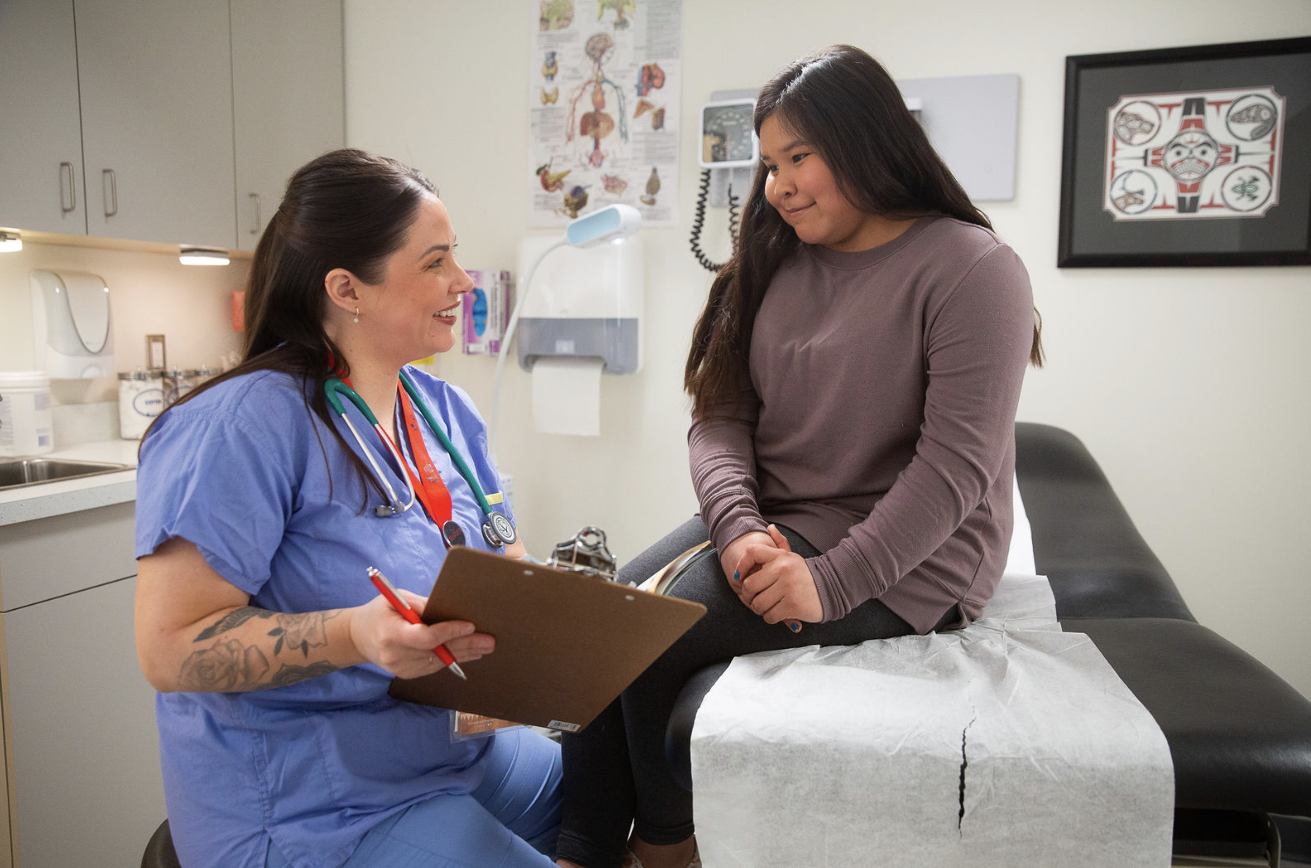 A nurse shows information on a clipboard to a young patient.